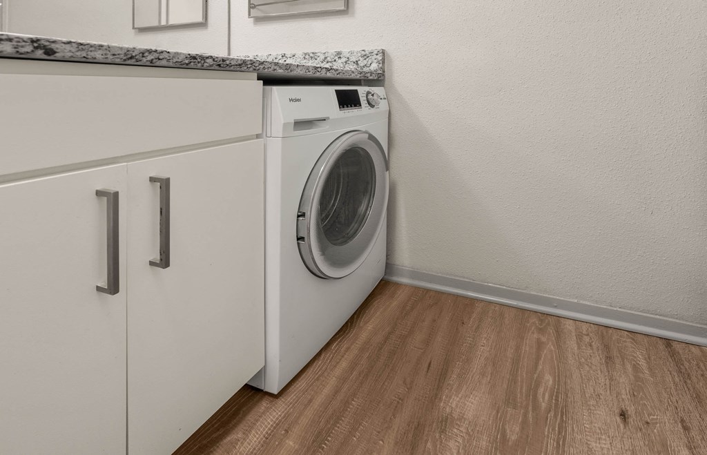 a front loading washer and dryer in a laundry room with a counter top a front loading washer and dryer in a laundry room with a counter top at South Lamar Village, Texas